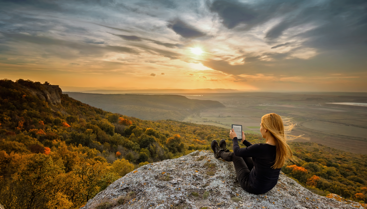 girl reading on the top of the hill by the sunset